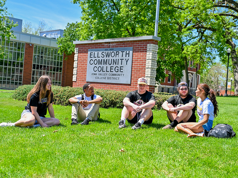 Ellsworth students sitting in lawn in front of ECC sign