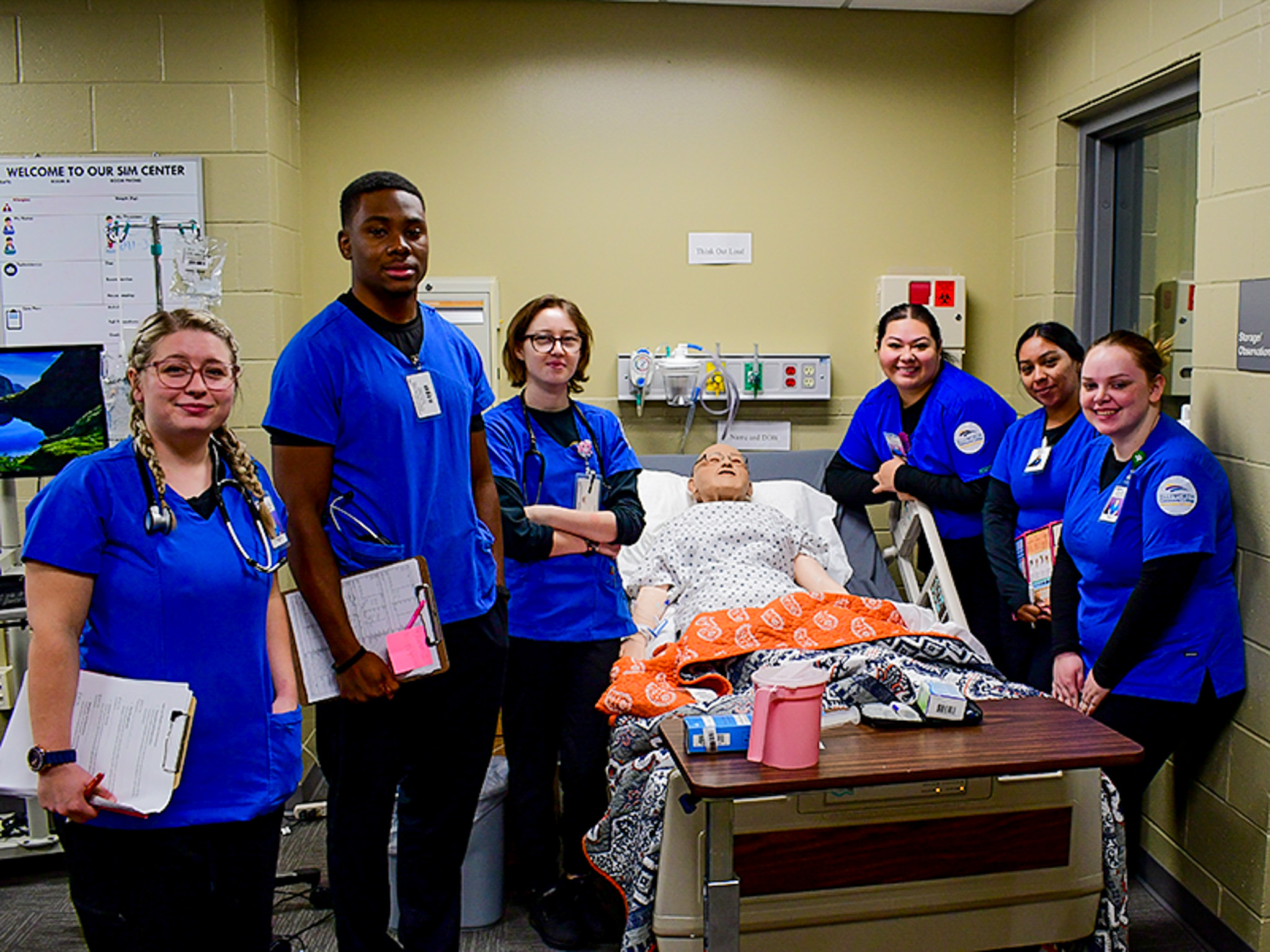 Nursing students gathered around a simulation mannequin.