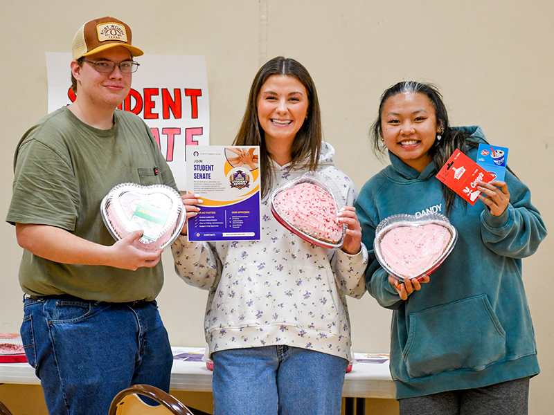 Three students during a Student Senate event, the Winter Carnival. Each student is a holding a different prize.