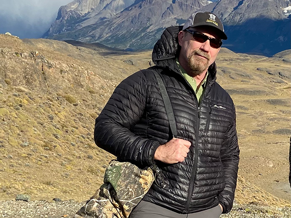 Paul Brooke Standing in the mountains of Chile with a camera around his shoulder