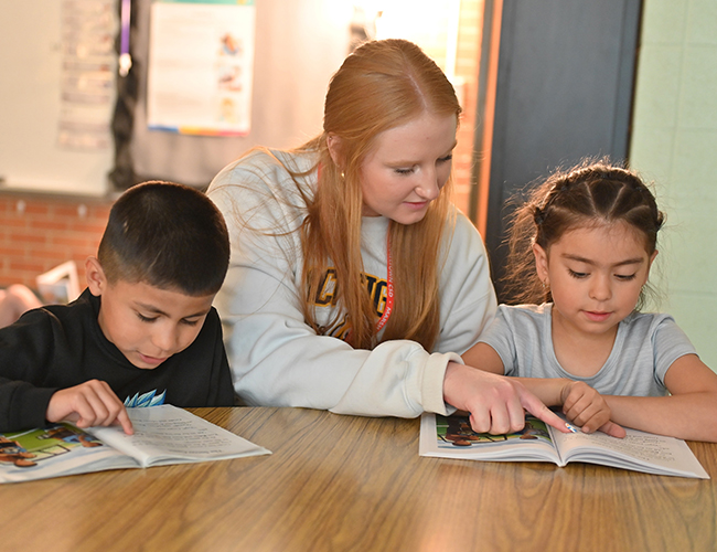 Childhood Education education student with two elementary students in school