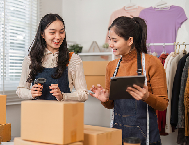 two females in store area unpacking boxes