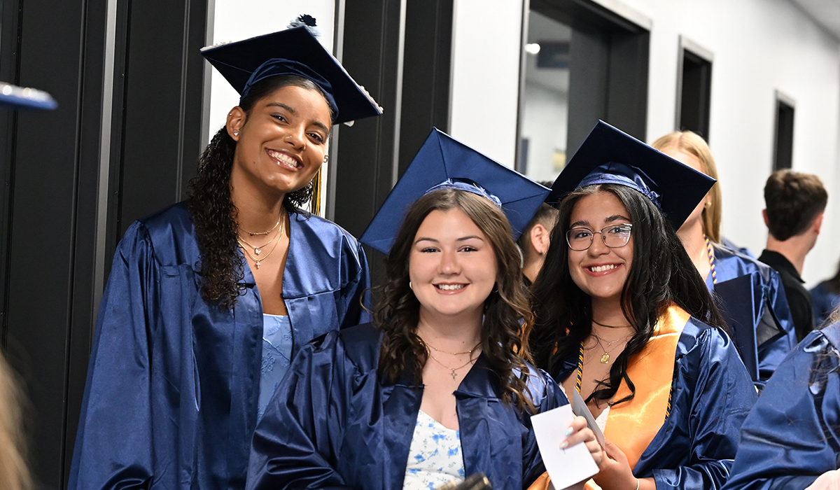 three girls in grad apparel smiling at the camera